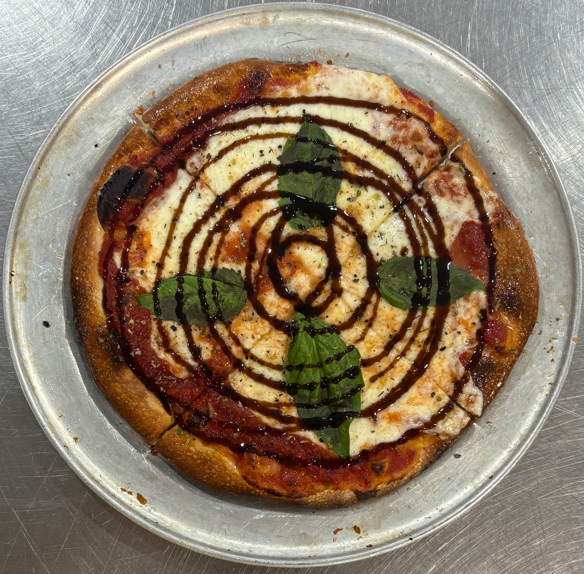 Pizza drizzled with balsamic glaze and fresh basil